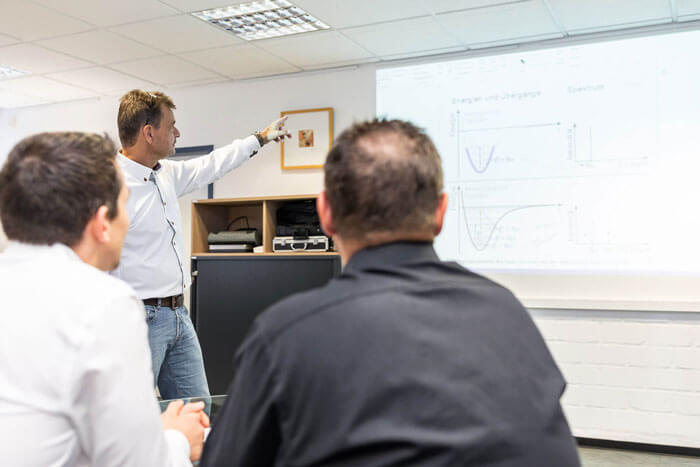 innovationen-schulungen-und-seminare Ein Mitarbeiter hält einen Vortrag während zwei Personen zuschauen