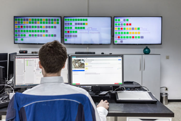 power-electric-motor-diagnostics Diagnostics employee sits in front of several screens and checks the monitoring data of electric motors