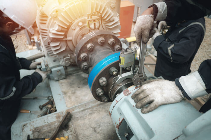 zwei Arbeiter bauen eine Pumpe in eine Anlage ein